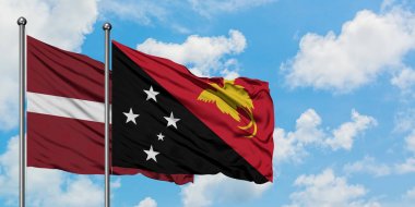 Letonya ve Papua Yeni Gine bayrağı birlikte beyaz bulutlu mavi gökyüzüne karşı rüzgarsal sallayarak. Diplomasi kavramı, uluslararası ilişkiler.