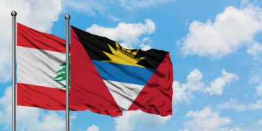 Lübnan ve Antigua ve Barbuda bayrağı birlikte beyaz bulutlu mavi gökyüzüne karşı rüzgarda sallayarak. Diplomasi kavramı, uluslararası ilişkiler.