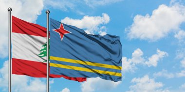 Lübnan ve Aruba bayrağı birlikte beyaz bulutlu mavi gökyüzüne karşı rüzgarda sallayarak. Diplomasi kavramı, uluslararası ilişkiler.