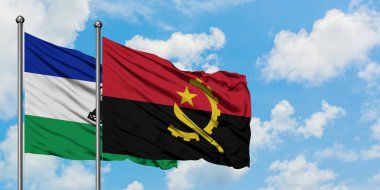 Lesotho ve Angola bayrağı birlikte beyaz bulutlu mavi gökyüzüne karşı rüzgarda sallayarak. Diplomasi kavramı, uluslararası ilişkiler.
