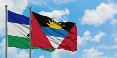 Lesotho ve Antigua ve Barbuda bayrağı birlikte beyaz bulutlu mavi gökyüzüne karşı rüzgarda sallayarak. Diplomasi kavramı, uluslararası ilişkiler.