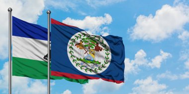 Lesotho ve Belize bayrağı birlikte beyaz bulutlu mavi gökyüzüne karşı rüzgarda sallayarak. Diplomasi kavramı, uluslararası ilişkiler.