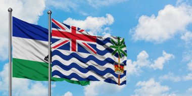 Lesotho ve İngiliz Hint Okyanusu Toprakları bayrağı birlikte beyaz bulutlu mavi gökyüzüne karşı rüzgarda sallayarak. Diplomasi kavramı, uluslararası ilişkiler.