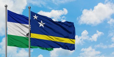Lesotho ve Curacao bayrağı birlikte beyaz bulutlu mavi gökyüzüne karşı rüzgarda sallayarak. Diplomasi kavramı, uluslararası ilişkiler.