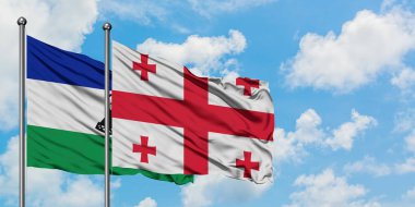 Lesotho ve Gürcistan bayrağı birlikte beyaz bulutlu mavi gökyüzüne karşı rüzgarda sallayarak. Diplomasi kavramı, uluslararası ilişkiler.