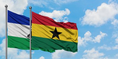 Lesotho ve Gana bayrağı birlikte beyaz bulutlu mavi gökyüzüne karşı rüzgarda sallayarak. Diplomasi kavramı, uluslararası ilişkiler.