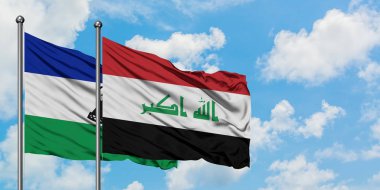 Lesotho ve Irak bayrağı birlikte beyaz bulutlu mavi gökyüzüne karşı rüzgarda sallayarak. Diplomasi kavramı, uluslararası ilişkiler.