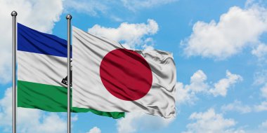 Lesotho ve Japonya bayrağı birlikte beyaz bulutlu mavi gökyüzüne karşı rüzgarda sallayarak. Diplomasi kavramı, uluslararası ilişkiler.