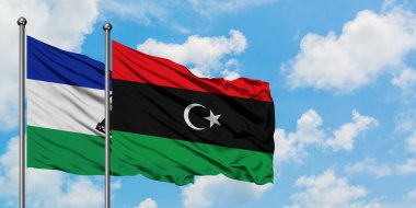 Lesotho ve Libya bayrağı birlikte beyaz bulutlu mavi gökyüzüne karşı rüzgarda sallayarak. Diplomasi kavramı, uluslararası ilişkiler.