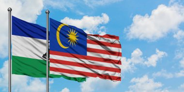 Lesotho ve Malezya bayrağı birlikte beyaz bulutlu mavi gökyüzüne karşı rüzgarda sallayarak. Diplomasi kavramı, uluslararası ilişkiler.