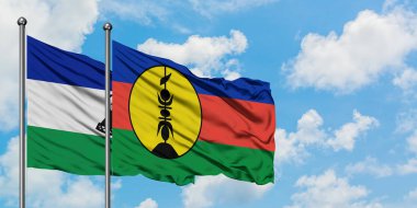 Lesotho and New Caledonia flag waving in the wind against white cloudy blue sky together. Diplomacy concept, international relations.