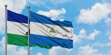 Lesotho and Nicaragua flag waving in the wind against white cloudy blue sky together. Diplomacy concept, international relations.