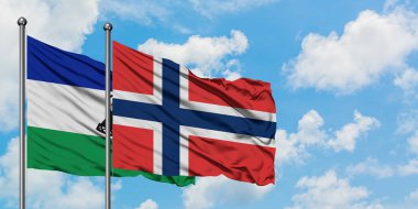 Lesotho and Norway flag waving in the wind against white cloudy blue sky together. Diplomacy concept, international relations.
