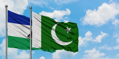 Lesotho and Pakistan flag waving in the wind against white cloudy blue sky together. Diplomacy concept, international relations.