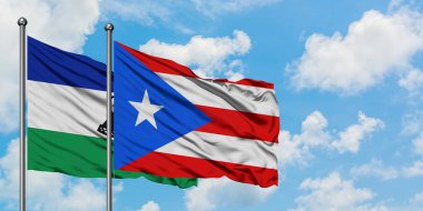 Lesotho and Puerto Rico flag waving in the wind against white cloudy blue sky together. Diplomacy concept, international relations.