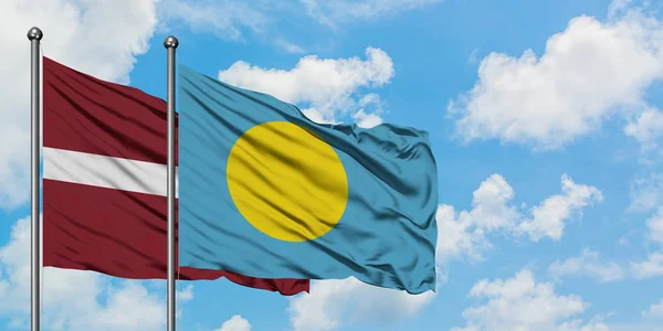 Lettország és Palau zászló integetett a szél ellen, fehér felhős kék ég együtt. Diplomáciai koncepció, nemzetközi kapcsolatok. — Stock Fotó