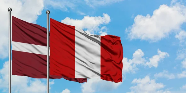Lettland och Peru flagga vifta i vinden mot vit grumlig blå himmel tillsammans. Diplomatisk koncept, internationella relationer. — Stockfoto