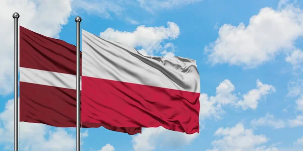 Lettland och Polen flagga vifta i vinden mot vit grumlig blå himmel tillsammans. Diplomatisk koncept, internationella relationer. — Stockfoto