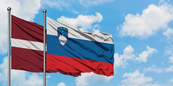 Latvia and Slovenia flag waving in the wind against white cloudy blue sky together. Diplomacy concept, international relations. — Stock Photo, Image