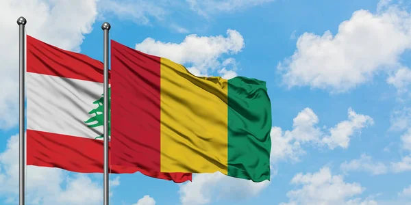 Bandera de Líbano y Guinea ondeando en el viento contra el cielo azul nublado blanco juntos. Concepto diplomático, relaciones internacionales . — Foto de Stock