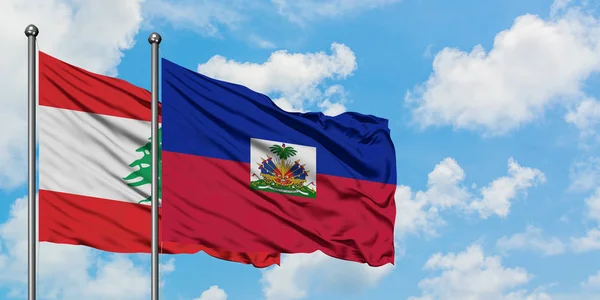 Libanon en Haïti vlag zwaaien in de wind tegen witte bewolkte blauwe hemel samen. Diplomatie concept, internationale betrekkingen. — Stockfoto