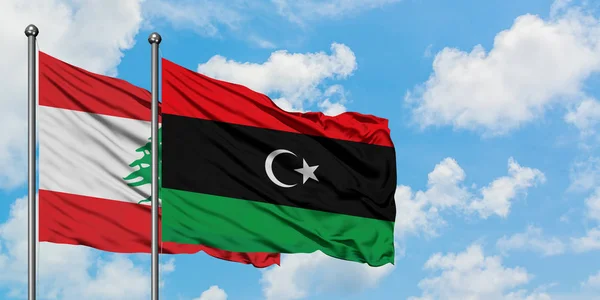 Bandera de Líbano y Libia ondeando en el viento contra el cielo azul nublado blanco juntos. Concepto diplomático, relaciones internacionales . — Foto de Stock