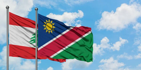 Libanon en Namibië vlag zwaaien in de wind tegen witte bewolkte blauwe hemel samen. Diplomatie concept, internationale betrekkingen. — Stockfoto