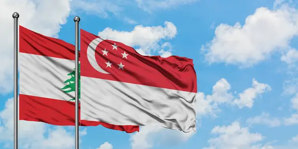Drapeau du Liban et de Singapour agitant dans le vent contre ciel bleu nuageux blanc ensemble. Concept de diplomatie, relations internationales . — Photo