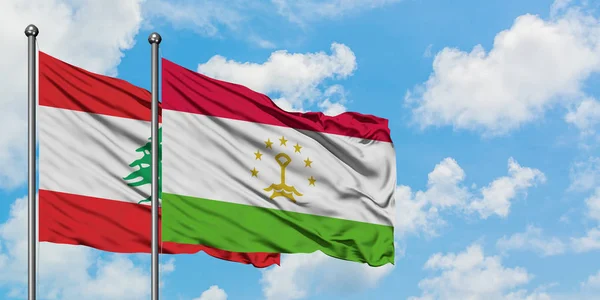 Bandera del Líbano y Tayikistán ondeando en el viento contra el cielo azul nublado blanco juntos. Concepto diplomático, relaciones internacionales . — Foto de Stock