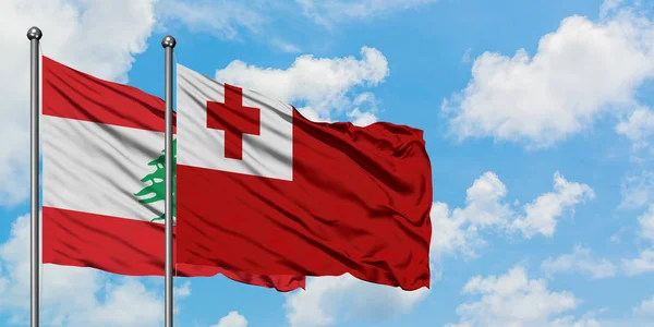 Bandera de Líbano y Tonga ondeando en el viento contra el cielo azul nublado blanco juntos. Concepto diplomático, relaciones internacionales . — Foto de Stock