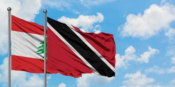 Lübnan ve Trinidad ve Tobago bayrağı birlikte beyaz bulutlu mavi gökyüzüne karşı rüzgarda sallayarak. Diplomasi kavramı, uluslararası ilişkiler. — Stok fotoğraf