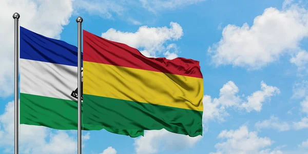 Bandera de Lesotho y Bolivia ondeando en el viento contra el cielo azul nublado blanco juntos. Concepto diplomático, relaciones internacionales . — Foto de Stock