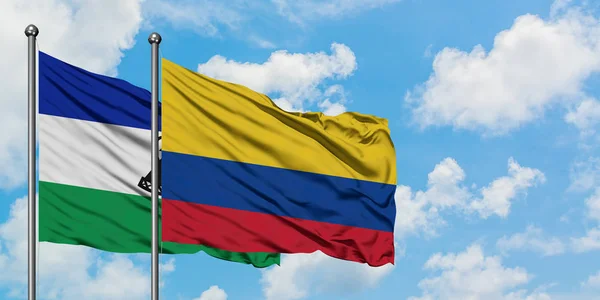 Η σημαία του Λεσότο και της Κολομβίας κουνώντας τον άνεμο ενάντια στον λευκό συννεφιασμένο γαλάζιο ουρανό. Φιλοσοφία της διπλωματίας, διεθνείς σχέσεις. — Φωτογραφία Αρχείου