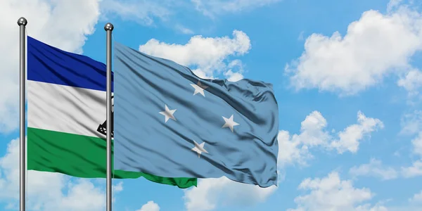 Bandera Lesotho y Micronesia ondeando en el viento contra el cielo azul nublado blanco juntos. Concepto diplomático, relaciones internacionales . — Foto de Stock