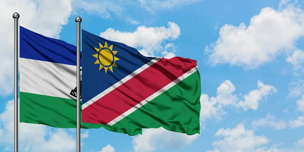Bandera de Lesotho y Namibia ondeando en el viento contra el cielo azul nublado blanco juntos. Concepto diplomático, relaciones internacionales . — Foto de Stock