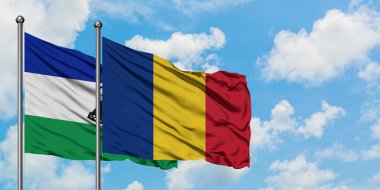 Lesotho and Romania flag waving in the wind against white cloudy blue sky together. Diplomacy concept, international relations.