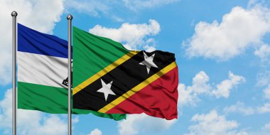 Lesotho and Saint Kitts And Nevis flag waving in the wind against white cloudy blue sky together. Diplomacy concept, international relations.