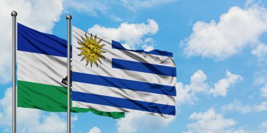 Lesotho ve Uruguay bayrağı birlikte beyaz bulutlu mavi gökyüzüne karşı rüzgarda sallayarak. Diplomasi kavramı, uluslararası ilişkiler.