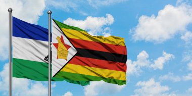 Lesotho ve Zimbabve bayrağı birlikte beyaz bulutlu mavi gökyüzüne karşı rüzgarda sallayarak. Diplomasi kavramı, uluslararası ilişkiler.
