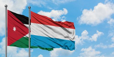 Ürdün ve Lüksemburg bayrağı birlikte beyaz bulutlu mavi gökyüzüne karşı rüzgarda sallayarak. Diplomasi kavramı, uluslararası ilişkiler.