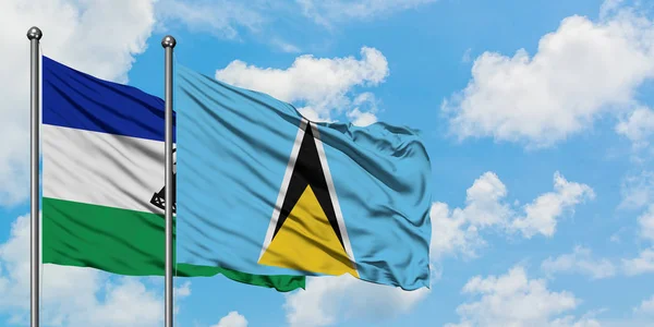 Lesotho and Saint Lucia flag waving in the wind against white cloudy blue sky together. Diplomacy concept, international relations. — Stockfoto