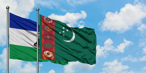 Bandera de Lesotho y Turkmenistán ondeando en el viento contra el cielo azul nublado blanco juntos. Concepto diplomático, relaciones internacionales . — Foto de Stock