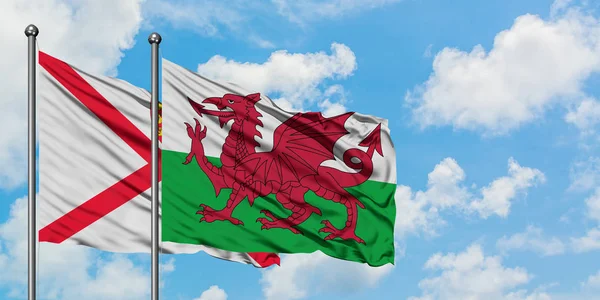 Jersey e País de Gales acenando com o vento contra o céu azul nublado branco juntos. Conceito de diplomacia, relações internacionais . — Fotografia de Stock