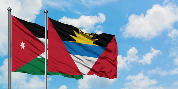 Jordania y Antigua y Barbuda bandera ondeando en el viento contra el cielo blanco azul nublado juntos. Concepto diplomático, relaciones internacionales . — Foto de Stock