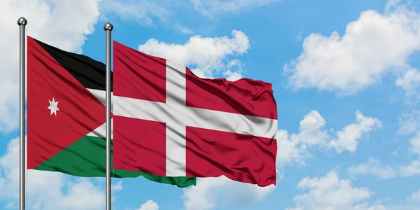 Bandera de Jordania y Dinamarca ondeando en el viento contra el cielo azul nublado blanco juntos. Concepto diplomático, relaciones internacionales . — Foto de Stock