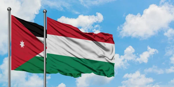 Bandera de Jordania y Hungría ondeando en el viento contra el cielo azul nublado blanco juntos. Concepto diplomático, relaciones internacionales . — Foto de Stock
