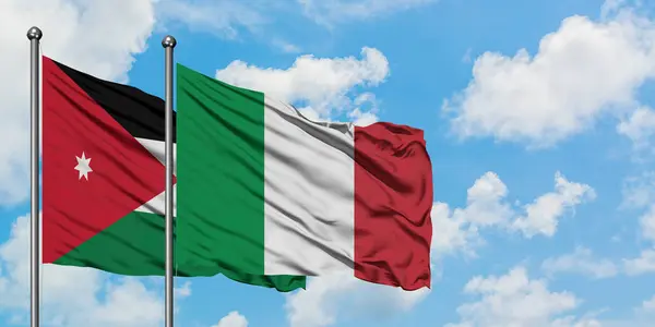 Bandera de Jordania e Italia ondeando en el viento contra el cielo azul nublado blanco juntos. Concepto diplomático, relaciones internacionales . — Foto de Stock