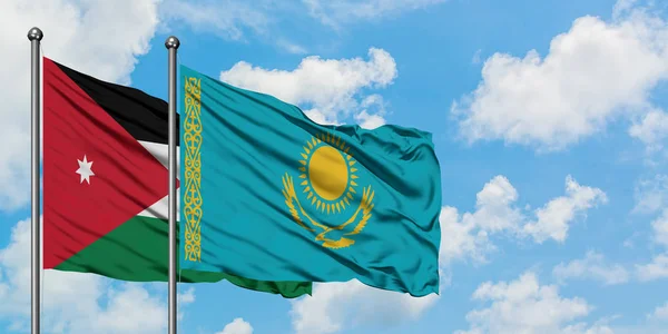 Bandera de Jordania y Kazajstán ondeando en el viento contra el cielo azul nublado blanco juntos. Concepto diplomático, relaciones internacionales . — Foto de Stock