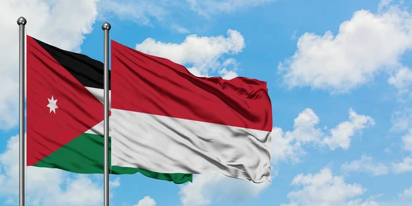 Bandera de Jordania y Mónaco ondeando en el viento contra el cielo azul nublado blanco juntos. Concepto diplomático, relaciones internacionales . — Foto de Stock