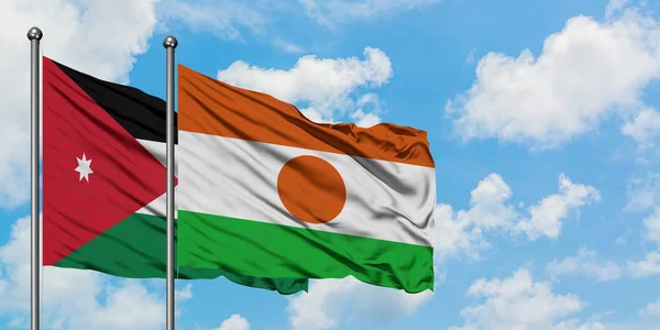 Bandera de Jordania y Níger ondeando en el viento contra el cielo azul nublado blanco juntos. Concepto diplomático, relaciones internacionales . — Foto de Stock